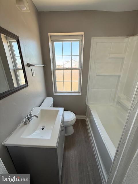 full bathroom with vanity, wood finished floors, baseboards, walk in shower, and toilet