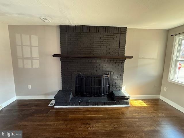 room details featuring visible vents, baseboards, a brick fireplace, and wood finished floors