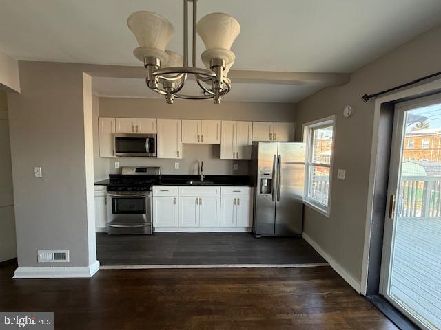 kitchen with visible vents, plenty of natural light, a sink, stainless steel appliances, and dark countertops