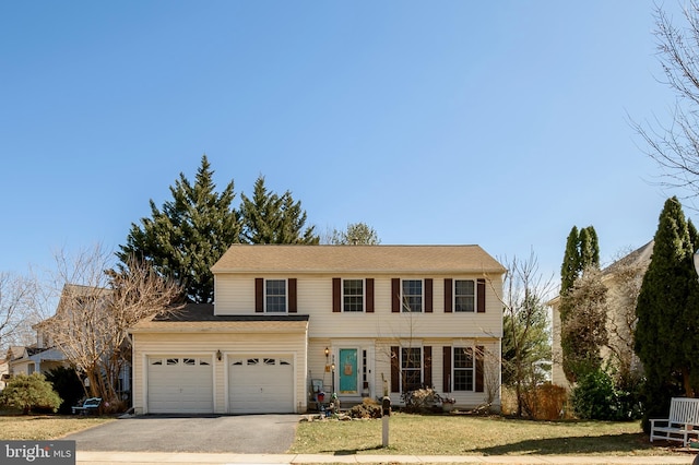 colonial house featuring aphalt driveway, a garage, and a front lawn