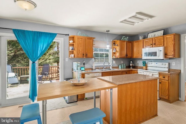 kitchen with white appliances, open shelves, a sink, light countertops, and a center island