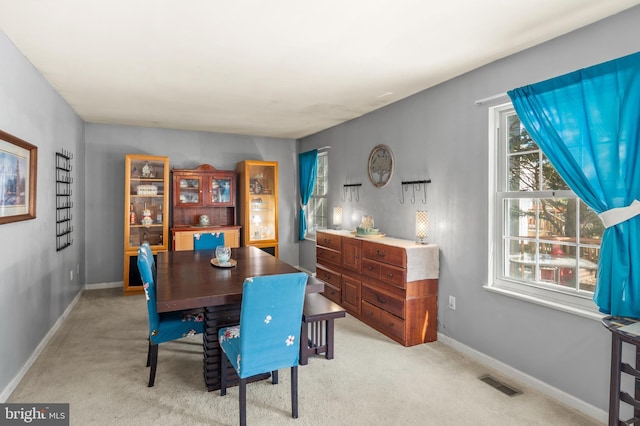 dining room with visible vents, light colored carpet, and baseboards