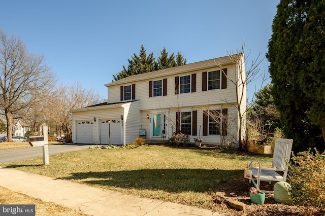 colonial home featuring driveway, an attached garage, and a front yard