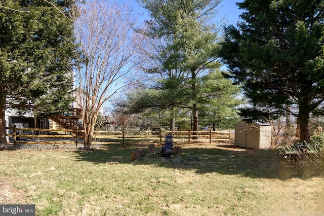 view of yard with an outbuilding, stairway, a storage unit, and fence