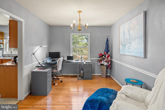 office space featuring an inviting chandelier, baseboards, light wood finished floors, and a sink