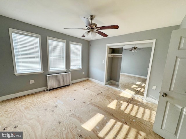 unfurnished bedroom with a closet, baseboards, radiator, and ceiling fan