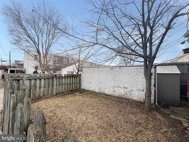 view of yard featuring an outbuilding, a storage shed, and a fenced backyard