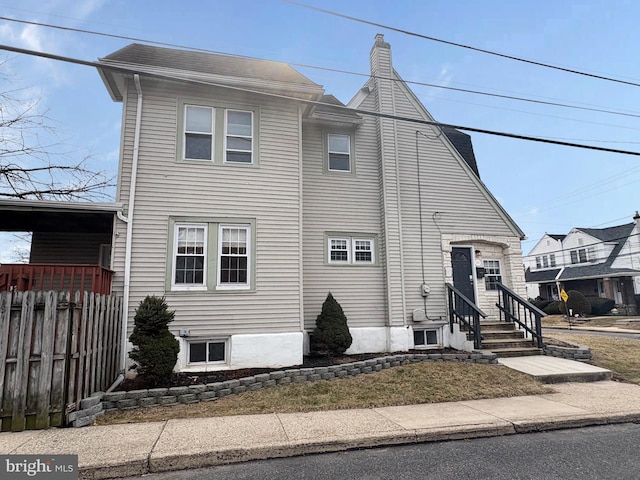 view of front of property with fence, a chimney, and entry steps