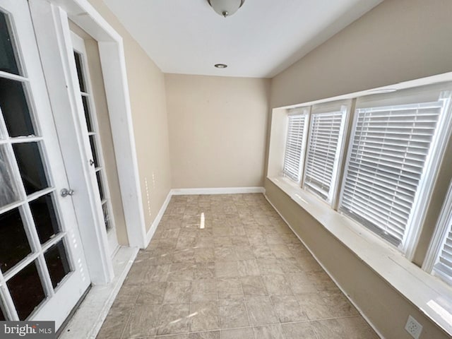 unfurnished room with baseboards