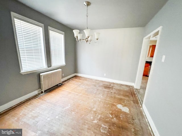 unfurnished dining area featuring baseboards, a notable chandelier, and radiator heating unit