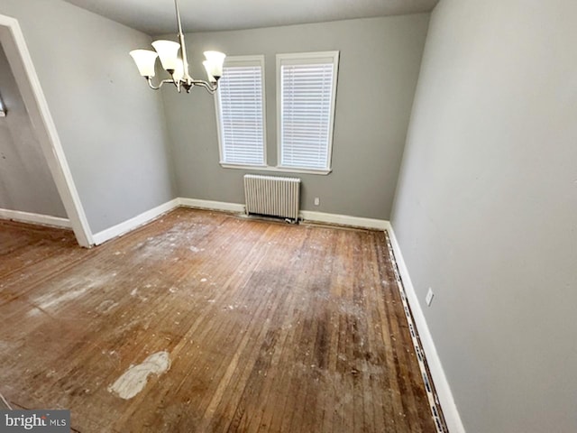 unfurnished dining area with baseboards, wood-type flooring, radiator, and a chandelier