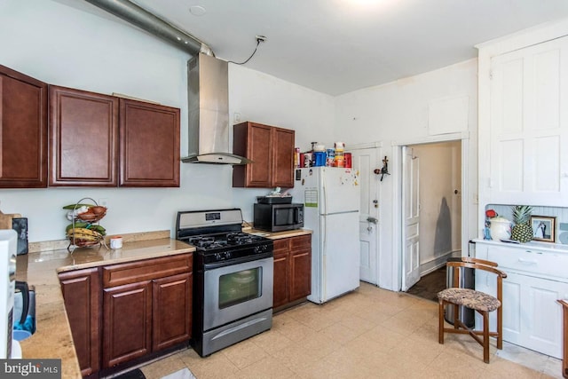 kitchen with light countertops, wall chimney exhaust hood, light floors, and stainless steel appliances