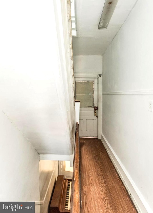 hall with baseboards and wood finished floors