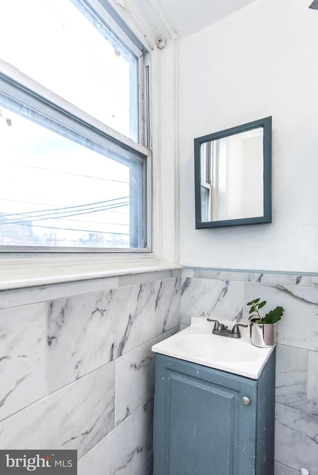 bathroom with vanity, tile walls, and a wainscoted wall