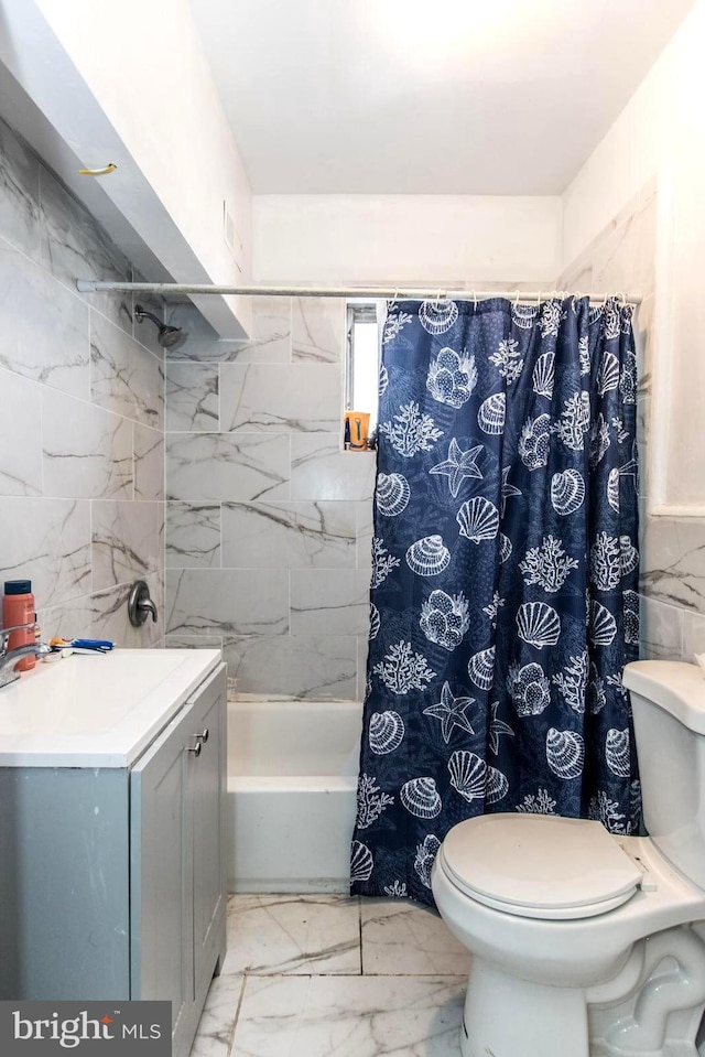 full bath featuring tile walls, toilet, shower / bath combination with curtain, vanity, and marble finish floor