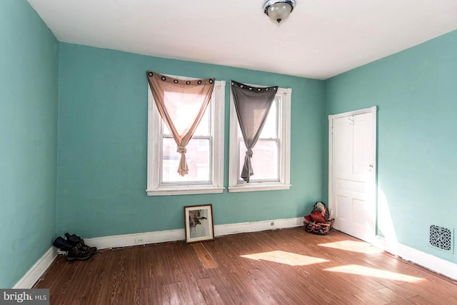 unfurnished room with visible vents, wood finished floors, and baseboards