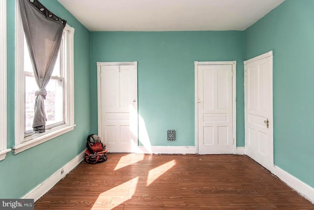 unfurnished bedroom with baseboards, multiple windows, and wood finished floors