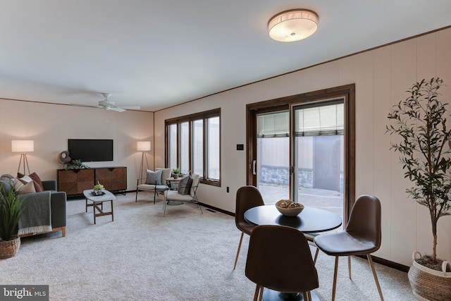 dining space featuring light carpet, baseboards, and ceiling fan