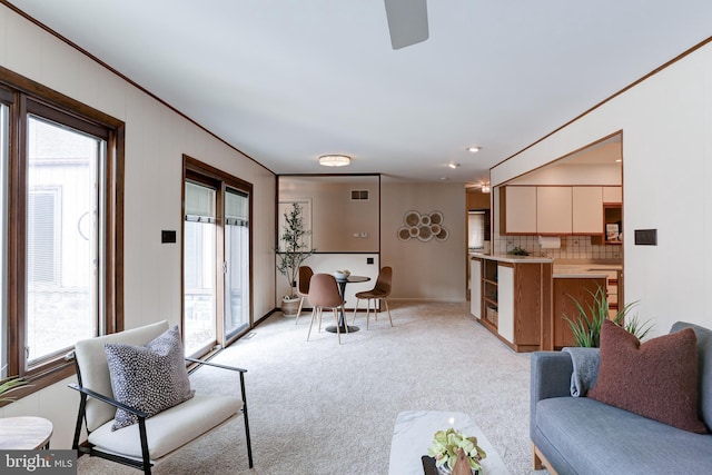 living room featuring visible vents, light colored carpet, and ornamental molding