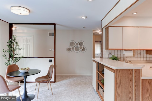 interior space with decorative backsplash, light countertops, visible vents, and light carpet