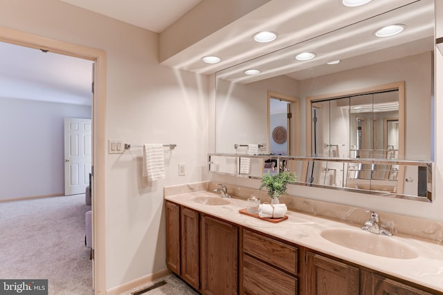 bathroom featuring a sink, visible vents, baseboards, and double vanity