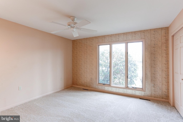 carpeted spare room featuring visible vents, ceiling fan, wallpapered walls, and baseboards