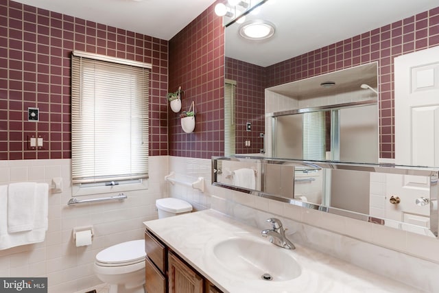 full bathroom with vanity, tile walls, toilet, and a shower with door