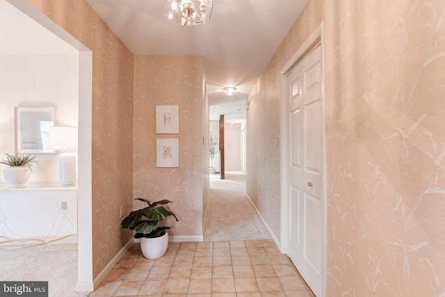 corridor with wallpapered walls, light tile patterned flooring, light colored carpet, and baseboards