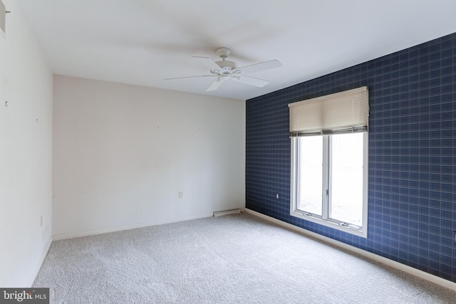 carpeted empty room featuring baseboards and ceiling fan