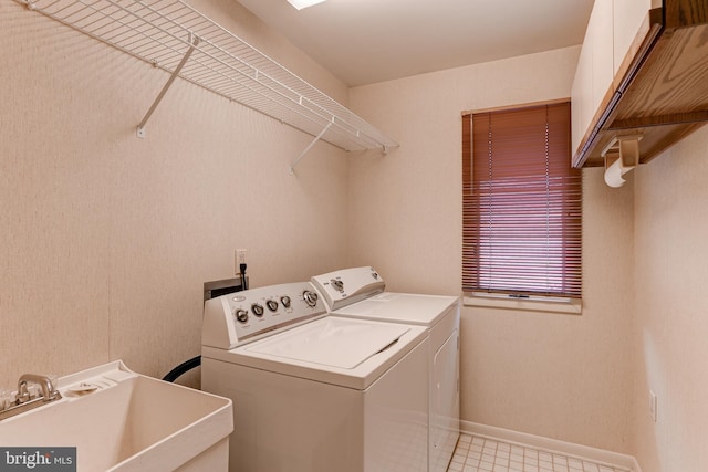 laundry room featuring a sink, baseboards, cabinet space, and independent washer and dryer