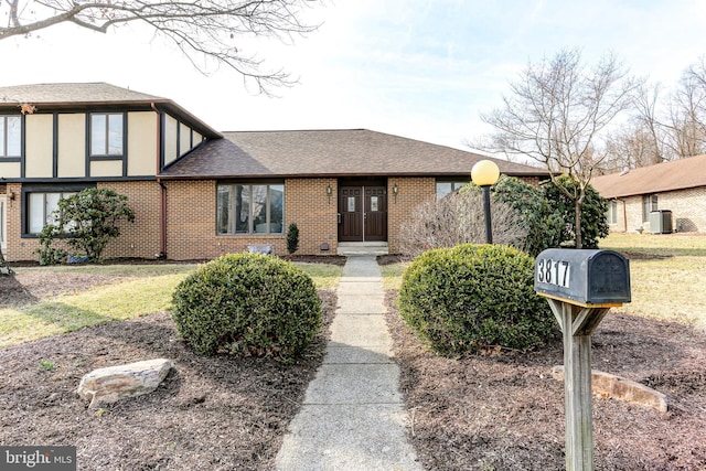 english style home featuring stucco siding, brick siding, and a shingled roof