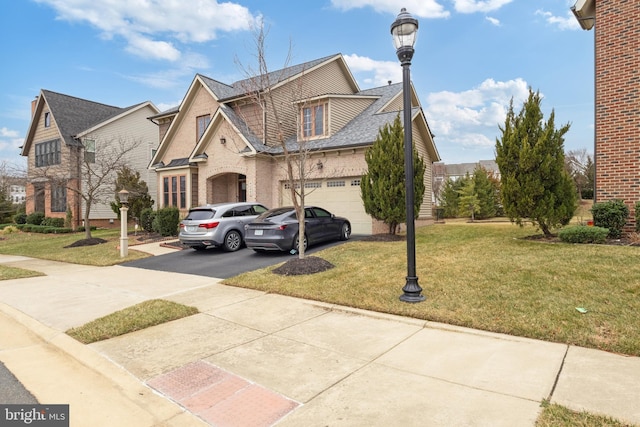 view of front facade featuring brick siding, an attached garage, a shingled roof, a front yard, and driveway