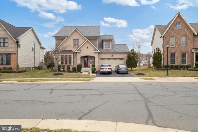 view of front of home featuring driveway, an attached garage, roof with shingles, and a front lawn