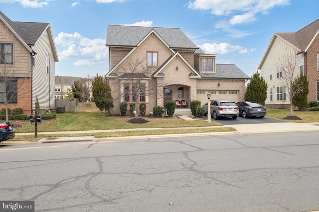 traditional home with concrete driveway, a front yard, a shingled roof, a garage, and brick siding