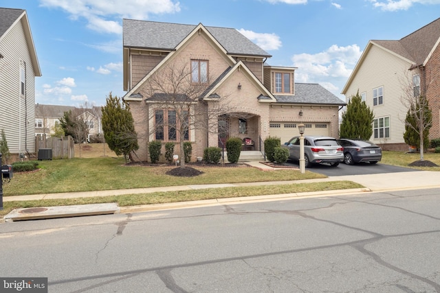 traditional-style home with brick siding, a shingled roof, a front lawn, concrete driveway, and a garage