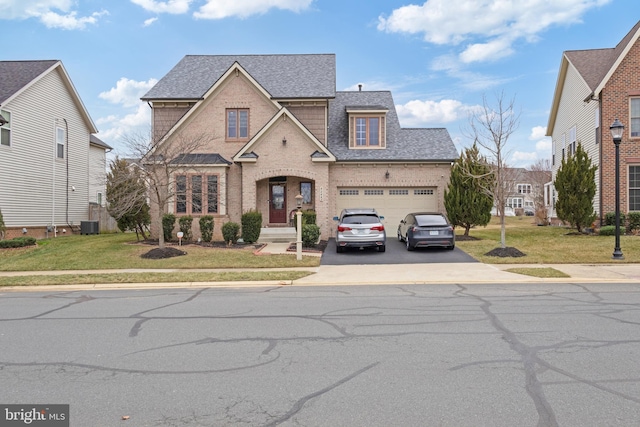 traditional home with driveway, brick siding, a front yard, and a shingled roof