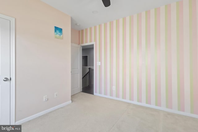 spare room featuring baseboards, carpet floors, a ceiling fan, and wallpapered walls