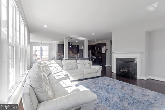 living area with a glass covered fireplace, recessed lighting, dark wood-style floors, and baseboards