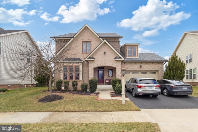 traditional home featuring a front lawn, brick siding, an attached garage, and driveway