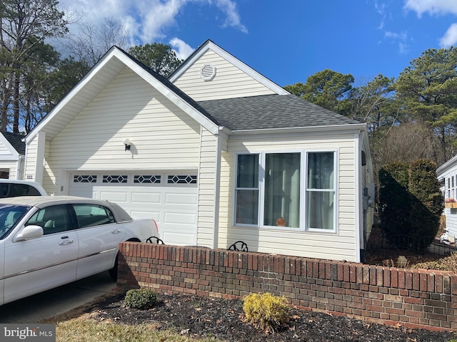 view of front of home with driveway, an attached garage, and a shingled roof