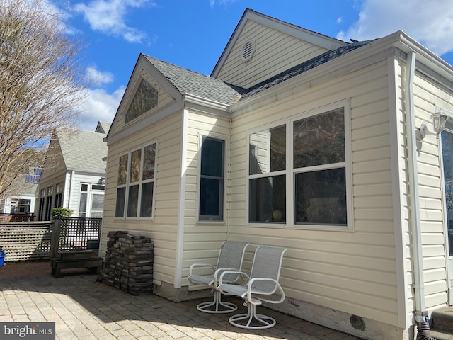 back of property with a patio and roof with shingles