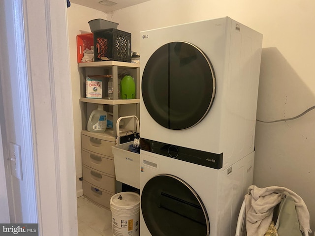 clothes washing area featuring marble finish floor, laundry area, and stacked washing maching and dryer