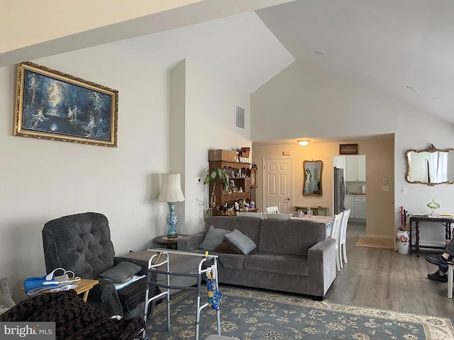 living area featuring wood finished floors, visible vents, and high vaulted ceiling