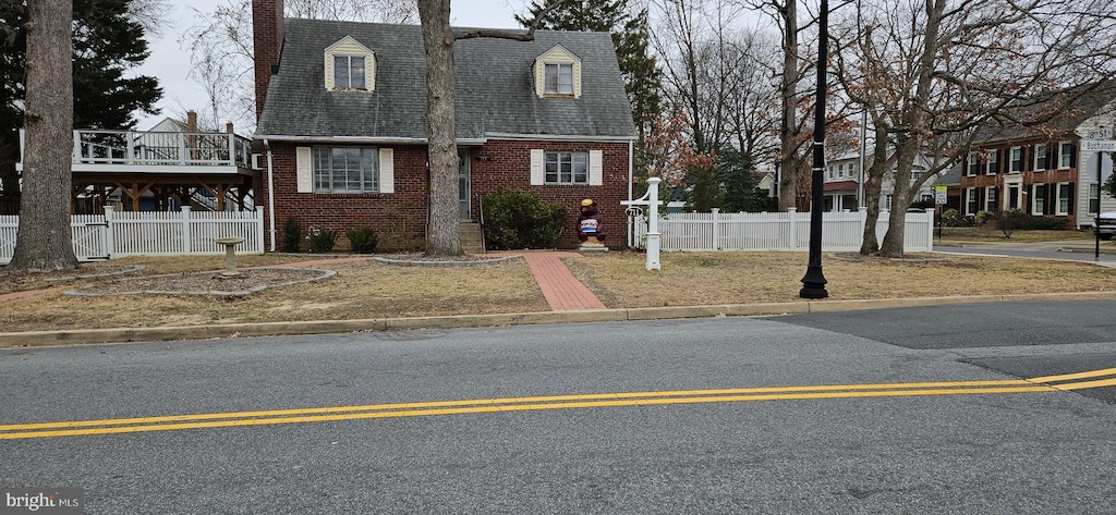 view of front of property with fence, brick siding, roof with shingles, and a chimney