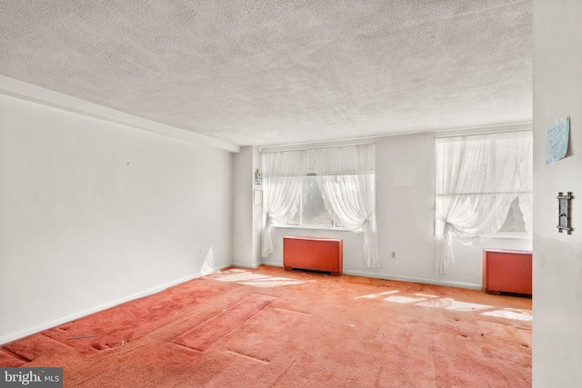 empty room with carpet flooring, a textured ceiling, and baseboards