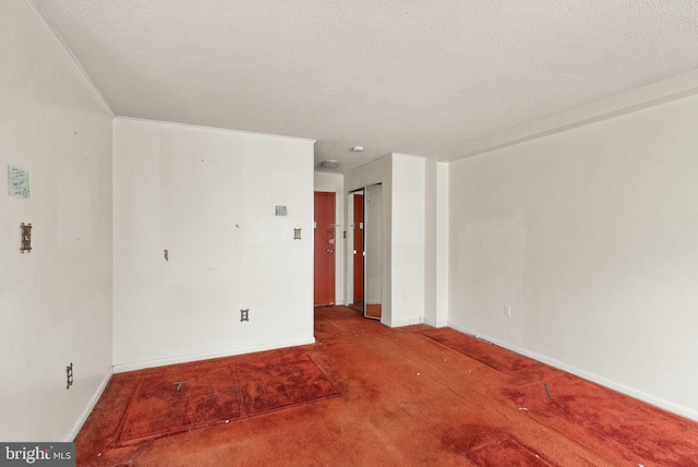 carpeted empty room featuring a textured ceiling, baseboards, and ornamental molding