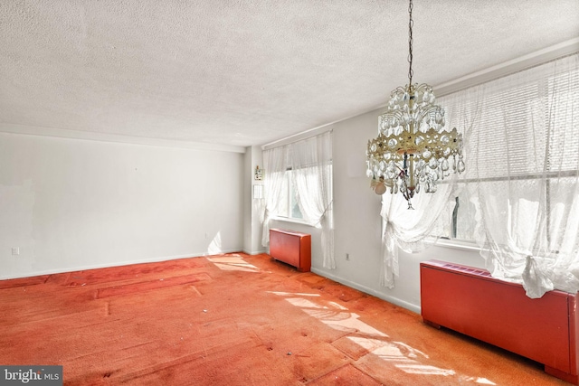 unfurnished dining area with a textured ceiling, radiator heating unit, an inviting chandelier, carpet flooring, and baseboards