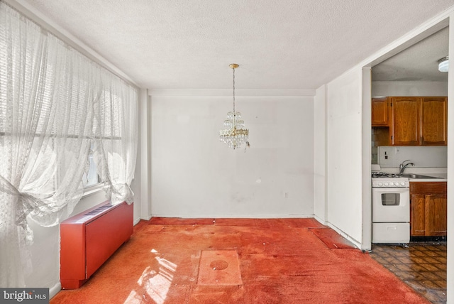 unfurnished dining area with a sink, an inviting chandelier, tile patterned floors, and a textured ceiling