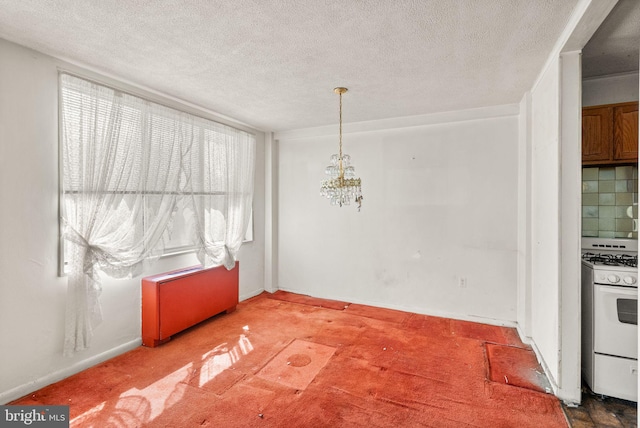 unfurnished dining area featuring baseboards, a textured ceiling, an inviting chandelier, and carpet flooring