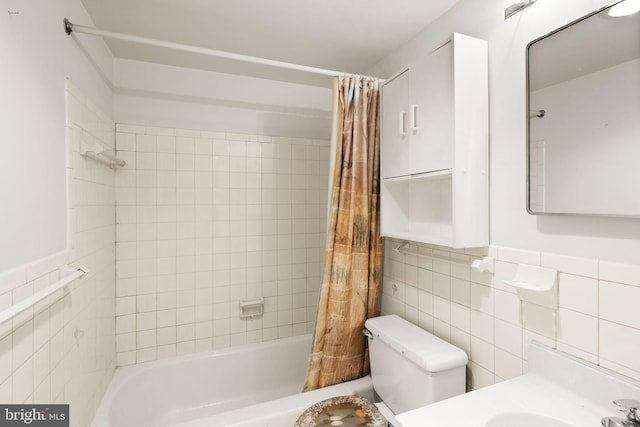 bathroom with wainscoting, toilet, tile walls, and shower / bath combo